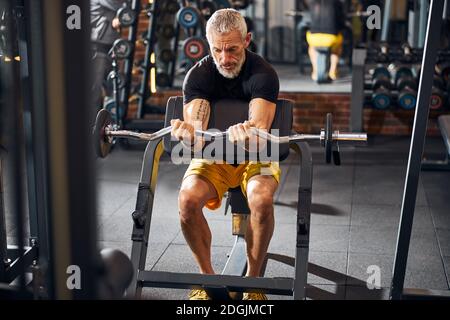 Fit uomo maturo che esegue l'addestramento di resistenza per bicipiti Foto Stock