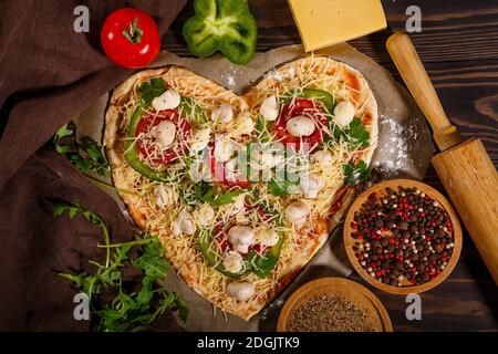 Pizza prima di cuocere, verdure e spezie su sfondo di legno scuro Foto Stock