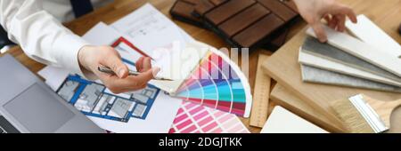 Mani maschili sopra la tabella su cui sono localizzati campioni di materiali di finitura e schemi di colore. Foto Stock