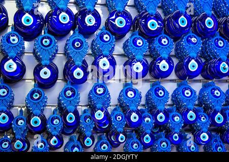 Vari amuleti blu perline male occhio boncugu Nazar che si aggancia lo sfondo della parete di colore bianco in turchia di antalya Foto Stock