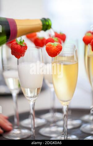 Vino frizzante o champagne e fragole da cui si versa il flacone Foto Stock