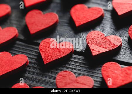 Bella valentines giorno sfondo con cuori di legno rosso su nero sfondo Foto Stock