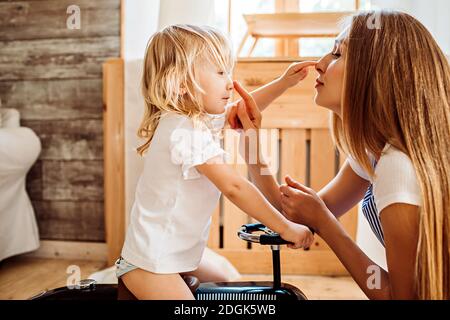 La giovane madre insegna alla sua piccola figlia semplici parole, mostrando parti del suo volto Foto Stock