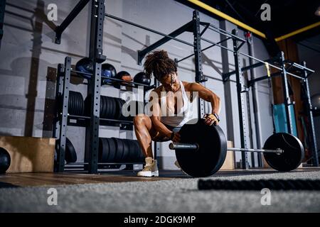 Sollevamento pesi femmina che carica il barbell prima della sessione di allenamento Foto Stock