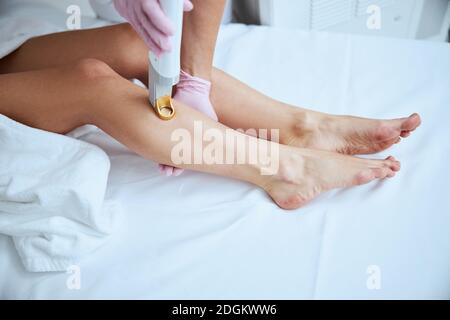 Cosmetologa femminile qualificata che fa una procedura di depilazione Foto Stock