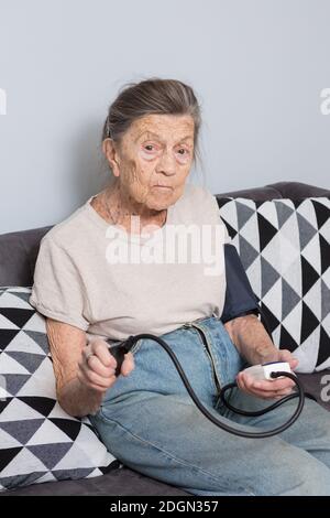 Il soggetto è persona molto anziano e problemi di salute. Una donna caucasica anziana, di 90 anni, con rughe e capelli grigi, siede a casa Foto Stock