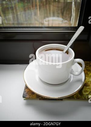 Una tazza di tè e un libro sul davanzale Foto Stock
