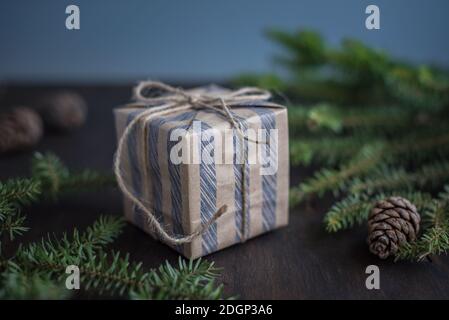 Sfondo di Natale. Confezione regalo avvolta in carta artigianale, rami di abete. Umore di nuovo anno. Foto Stock