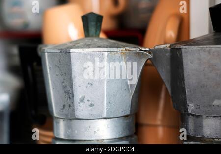 Vista ravvicinata di una vecchia caffettiera arrugginita all'interno di una dispensa. Graffi e segni di usura vicino al beccuccio. Oggetto di disegno. Cultura italiana Foto Stock