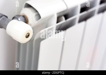 vista ravvicinata della manopola bianca che regola la temperatura del radiatore. Riscaldamento e stagione invernale Foto Stock