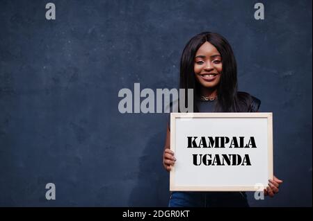 Donna africana tiene una lavagna bianca con iscrizione Kampala Uganda. La città più popolosa in Africa concetto. Foto Stock