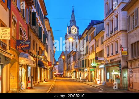 Scena di strada lungo la Rue des Alpes a Yverdon les Bains, Svizzera, con la torre della Collegiata Foto Stock