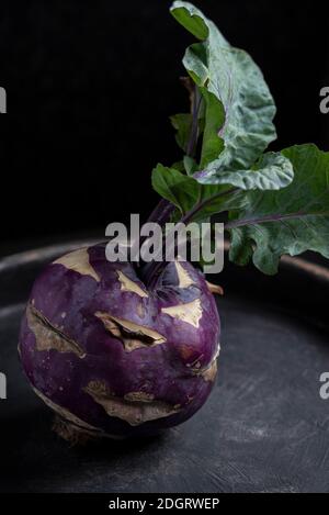 Un kohlrabi viola su sfondo nero ancora vita scuro fotografia alimentare Foto Stock