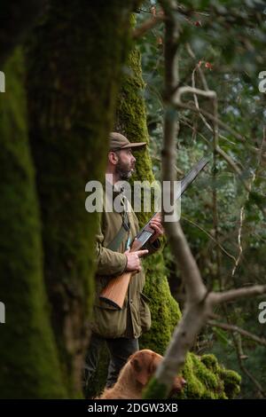 uomo con fucile a caccia di piccioni nel bosco Foto Stock