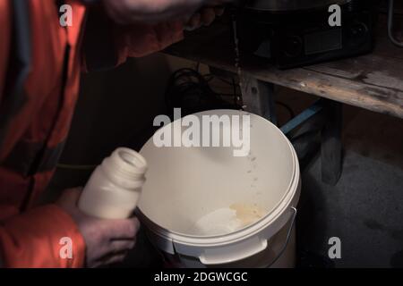 Riempire la birra giovane appena prodotta in un secchiello grande per la fermentazione durante il processo di preparazione della birra in garage a. casa Foto Stock
