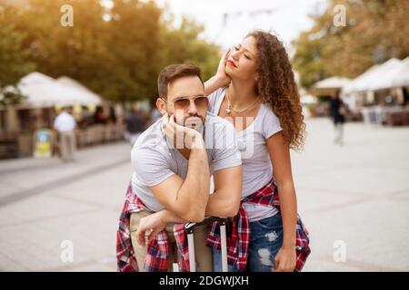 Giovane usurato fuori la coppia carina è appoggiata contro la loro borsa mentre attende il loro trasporto per arrivare. Foto Stock