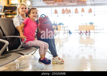 Felice madre e figlia giocando una partita in aeroporto prima dell'imbarco Foto Stock