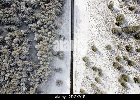 Vista aerea della strada vuota coperta di neve nella foresta invernale. Foto di alta qualità. Foto Stock