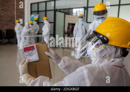 Un paziente COVID-19 lancia il suo scrutinio mentre un ufficiale sanitario rivestito in tuta di nocciolo guarda a una struttura di isolamento COVID-19, che ospita 49 elettori, a South Tangerang, Banten Foto Stock