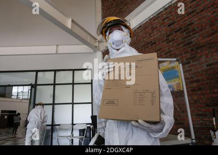 Un paziente COVID-19 lancia il suo scrutinio mentre un ufficiale sanitario rivestito in tuta di nocciolo guarda a una struttura di isolamento COVID-19, che ospita 49 elettori, a South Tangerang, Banten Foto Stock