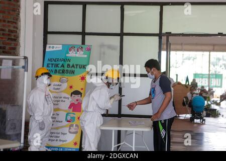 Un paziente COVID-19 lancia il suo scrutinio mentre un ufficiale sanitario rivestito in tuta di nocciolo guarda a una struttura di isolamento COVID-19, che ospita 49 elettori, a South Tangerang, Banten Foto Stock