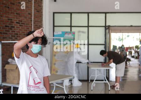 Un paziente COVID-19 lancia il suo scrutinio mentre un ufficiale sanitario rivestito in tuta di nocciolo guarda a una struttura di isolamento COVID-19, che ospita 49 elettori, a South Tangerang, Banten Foto Stock