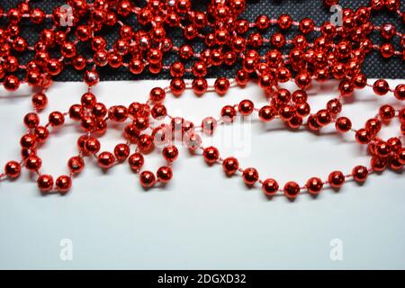 Le perle rosse di Capodanno e di Natale per l'albero di Capodanno sono casualmente sparse su sfondi bianchi e neri. Foto Stock