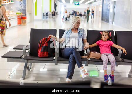 Felice madre e figlia giocando una partita in aeroporto prima dell'imbarco Foto Stock