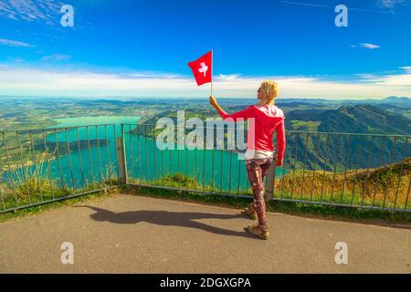 Donna con bandiera svizzera guardando panorama alpino dalla cima Rigi-Kulm del Monte Rigi. Turismo nel Cantone di Lucerna, Svizzera Centrale. Panorami incredibili Foto Stock