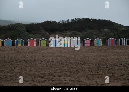 Colorata fila di capanne sulla spiaggia a Saunton Sands in un giorno cupo coperto tutto chiuso fuori stagione. Foto Stock