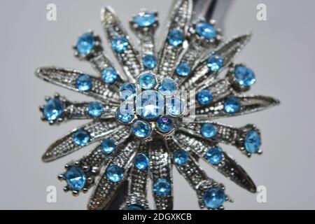 Una grande bella gioielleria femminile in metallo con pietre blu, incisioni, una forma insolita si trova su uno sfondo bianco opaco. Foto Stock