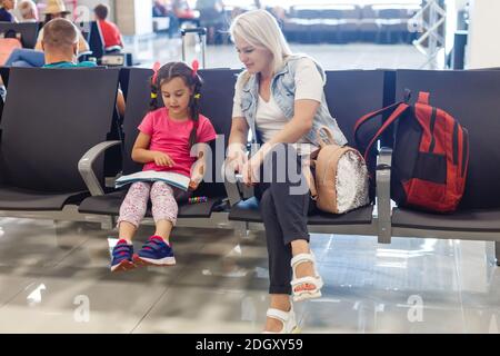 Felice madre e figlia giocando una partita in aeroporto prima dell'imbarco Foto Stock