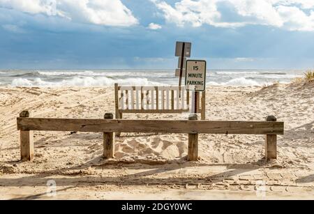 Panca di legno e segni con oceano sullo sfondo a Town Line Beach, wainsscott, NY Foto Stock