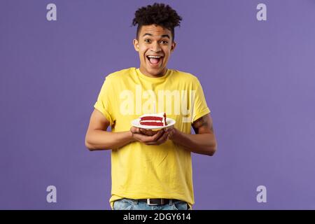 Buon compleanno a me. Ritratto di un uomo ispanico eccitato e ottimista, con i dreads che celebrano il b-day, tenendo una torta con la candela illuminata Foto Stock