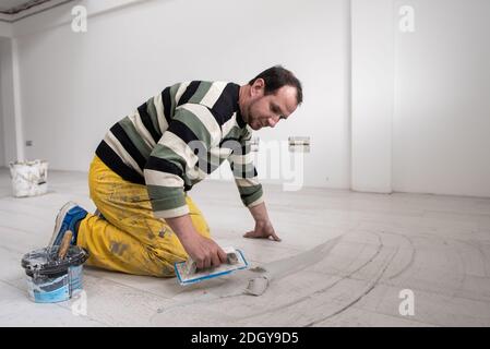 Piastrellatrici che riempiono lo spazio tra le piastrelle in ceramica effetto legno Foto Stock