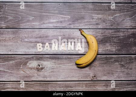 Banana frutta gialla con lettere di legno Foto Stock