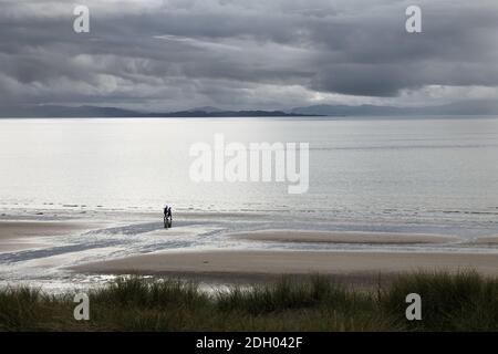 Due persone camminando su una spiaggia deserta con Nubi di pioggia in avvicinamento, Sands Bay, Gairloch, Scozia, Regno Unito Foto Stock