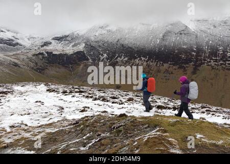 Two Walker vicino alla cima del outerside con il View Towards Force Crag Mine e un Cloud Covered Grisedale Pike, Lake District, Cumbria, Regno Unito Foto Stock