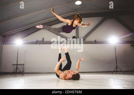 Il tema dell'Acroyoga e dello Yoga pone. Acroyogis pratica. Con studio Backlight. L'uomo base lancia il paps donna Flyer in f Foto Stock
