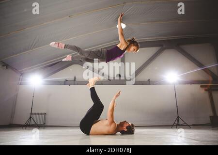 Il tema dell'Acroyoga e dello Yoga pone. Acroyogis pratica. Con studio Backlight. L'uomo base lancia il paps donna Flyer in f Foto Stock