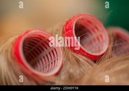 Parrucchiere arricciando i capelli di una donna bionda Foto Stock