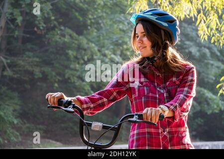 Oggetto modalità ecologica di trasporto bicicletta. Bella giovane donna kasazy che indossa un casco blu e lunghi capelli posa in piedi ne Foto Stock