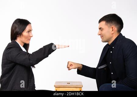 Una donna forte vince una battaglia con un uomo. Partner commerciali e gioco d'affari su sfondo bianco. Foto Stock