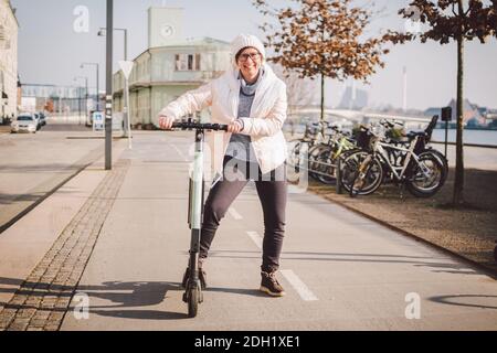 Donna turistica in affitto scooter elettrico nella capitale danese Copenhagen. Femmina che tiene la manopola del piantone dello sterzo con scooter elettrico Foto Stock