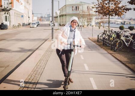 Donna turistica in affitto scooter elettrico nella capitale danese Copenhagen. Femmina che tiene la manopola del piantone dello sterzo con scooter elettrico Foto Stock