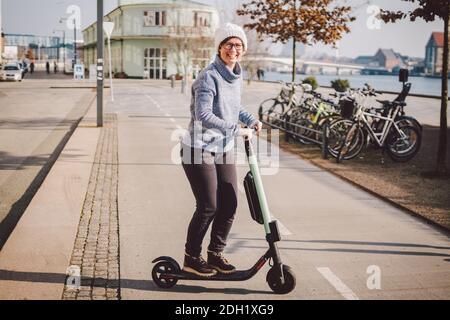 Donna turistica in affitto scooter elettrico nella capitale danese Copenhagen. Femmina che tiene la manopola del piantone dello sterzo con scooter elettrico Foto Stock