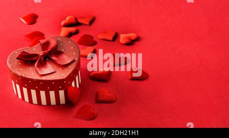 Confezione regalo con forma a cuore e cuori su sfondo rosso Foto Stock