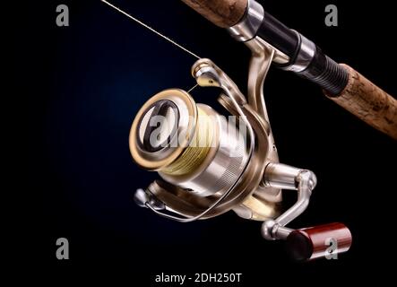 attrezzatura da pesca spinnig con bobina su sfondo scuro Foto Stock