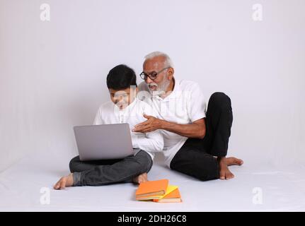 Nonno indiano che insegna la scuola o l'insegnamento a casa del nipote. Foto Stock