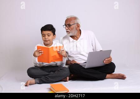 Nonno indiano che insegna la scuola o l'insegnamento a casa del nipote. Foto Stock